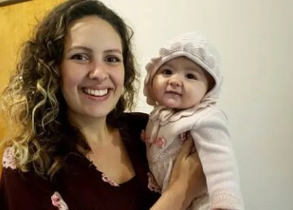 A smiling mother holding her baby daughter