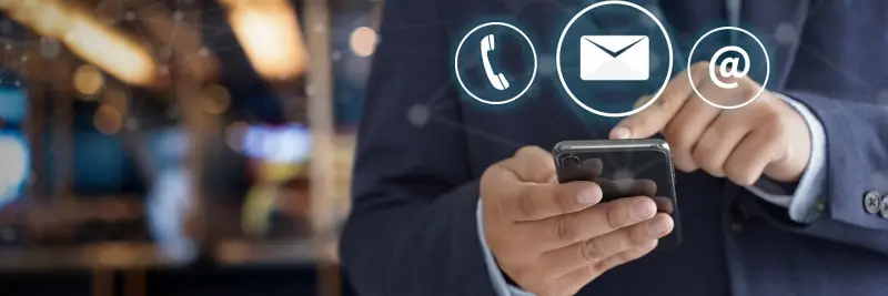 A hand holding a phone with call, email and message icons