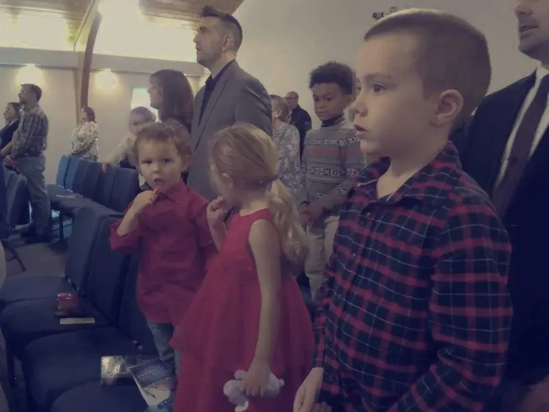 Children standing with their families during a worship service