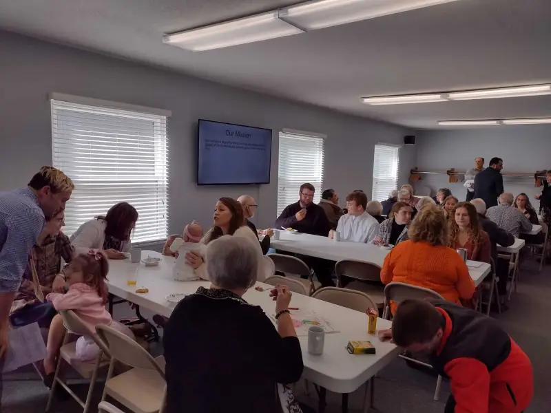 Church members sharing a meal around tables in the fellowship hall