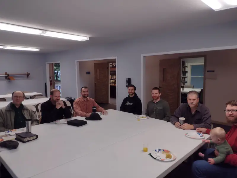 Men gathered around a table for the monthly breakfast