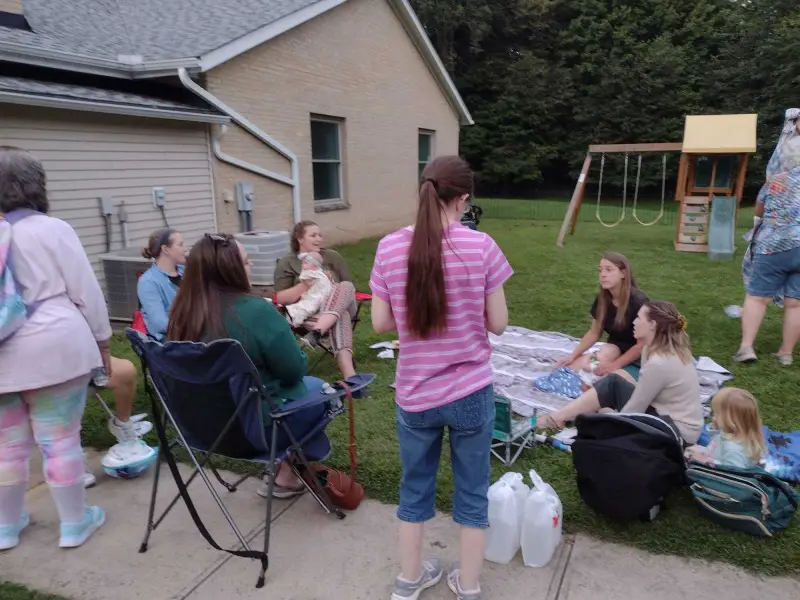 Women and children gathered outdoors on blankets and lawn chairs